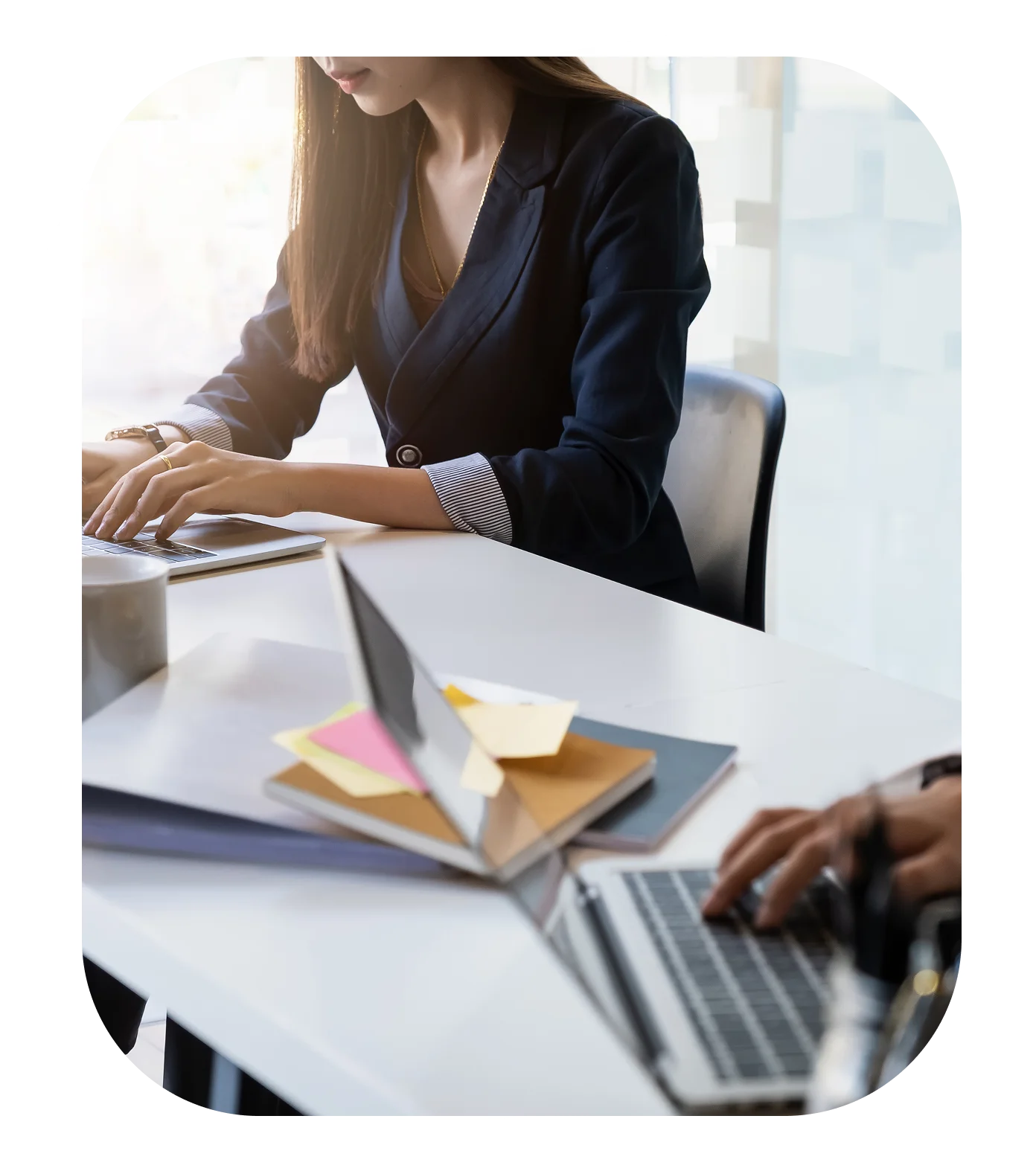 Two people working on laptops at desk.